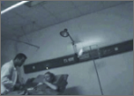A grainy, blue-tinted, low-light image shows a doctor attending to Jessica Lynch in her hospital bed.